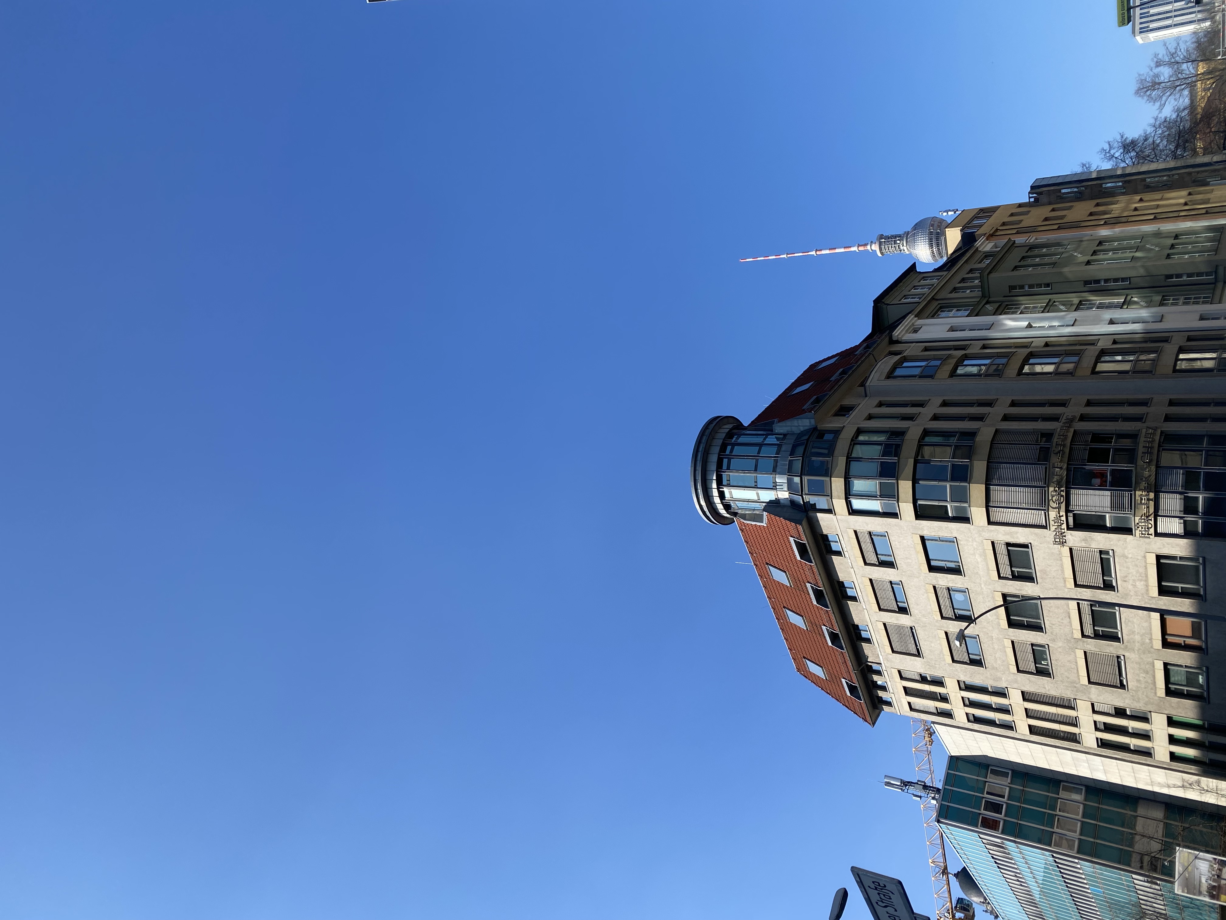 The Fernsehturm sphere appearing to balance on the curved roof of a glass-domed building below